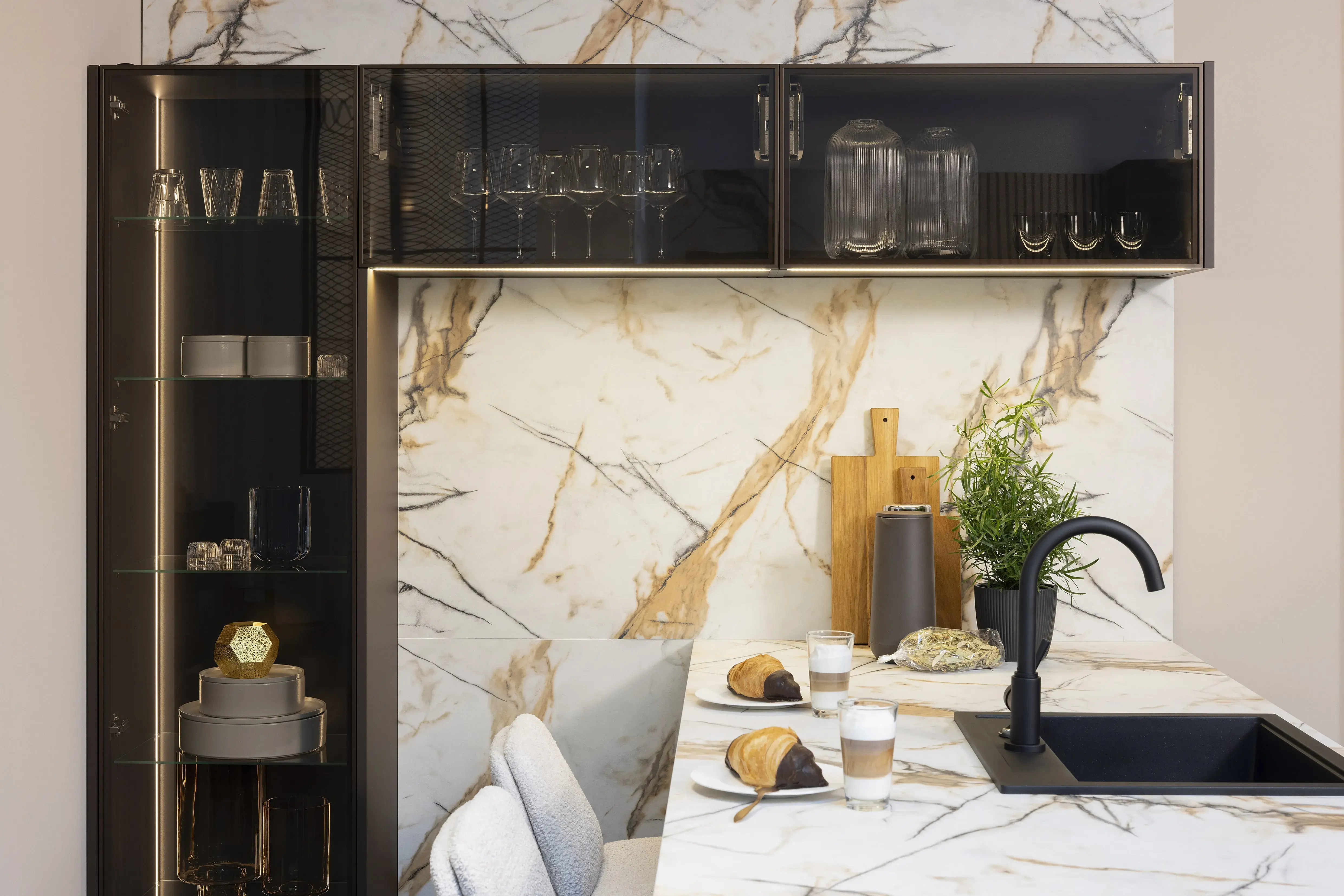 Moderne Küche mit Marmoroptikwand, schwarzem Wasserhahn und gedecktem Frühstückstisch.